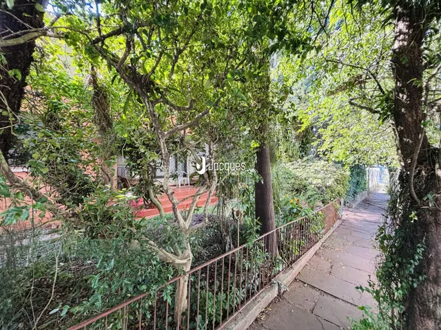 Vista externa da propriedade com vegetação densa e caminho lateral.