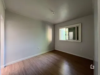 Ambiente interno de uma sala com piso de madeira clara.