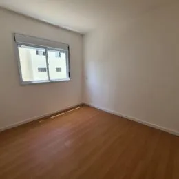 Vista interna de um cômodo com piso de madeira e janela.