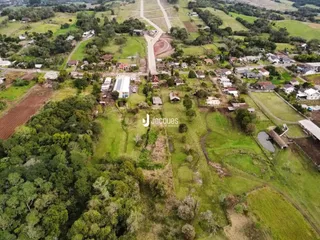 Vista aérea de uma área rural com vegetação e campos no Brasil.