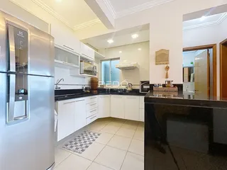 Vista da cozinha moderna com armários brancos e bancadas escuras.