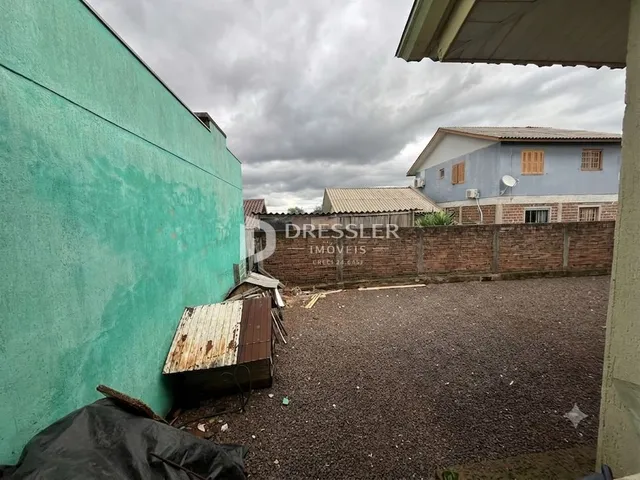 Fachada de uma residência em Lajeado, Brasil, com parede verde e muro de tijolos.