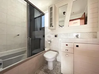 Interior de um banheiro com box de vidro e revestimento cerâmico.