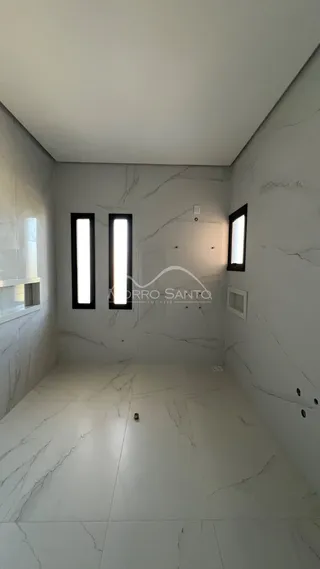 Hall de corredor com piso de mármore claro e janelas verticais.