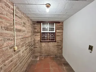 Corredor interno com paredes de tijolo aparente e piso de cerâmica.