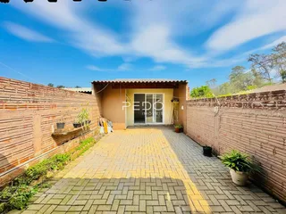 Fachada de uma propriedade com paredes de tijolo e pátio pavimentado.