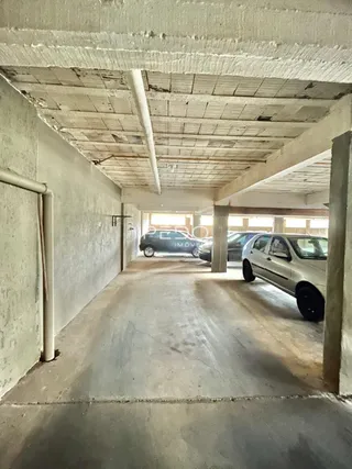 A foto mostra um corredor interno com teto de concreto aparente.