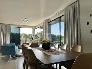 Sala de jantar com mesa de madeira e vista para o exterior.
