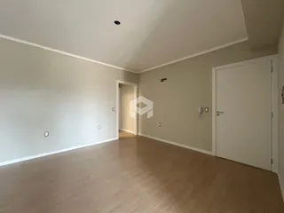 Um corredor interno com piso de madeira clara e paredes brancas.