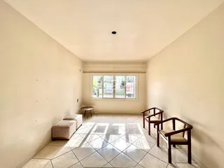 Sala de estar com piso de cerâmica e móveis de madeira clara.