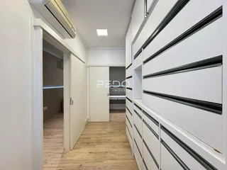 Hall de entrada com piso de madeira e armários brancos.