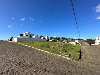Vista externa de uma propriedade com área gramada e céu azul.