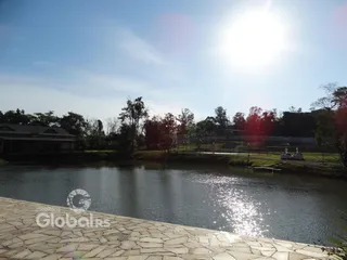 Vista da propriedade com um corpo d'água e vegetação ao fundo.