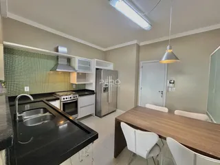 Foto da cozinha com armários brancos e bancada escura.