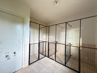 Vista interna de um corredor com divisórias de tela metálica preta.