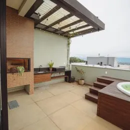 Uma área externa com piso de cerâmica sob uma estrutura de pergolado.