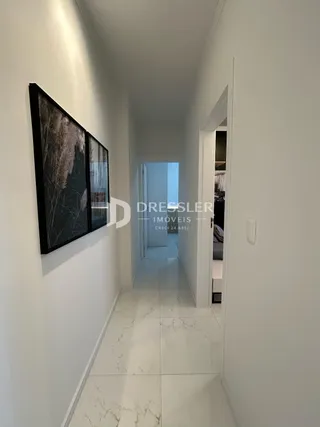 Corredor interno de uma residência com paredes brancas e piso claro.