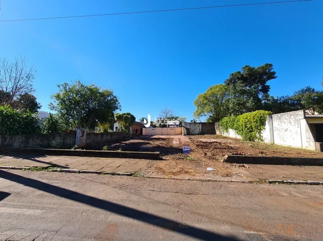 Vista externa de uma propriedade com muro e área de terra.
