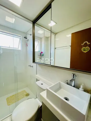 Foto interna de um banheiro com box de vidro e vaso sanitário branco.
