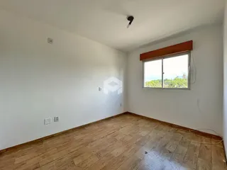 Ambiente interno de uma sala com piso de madeira e janela.