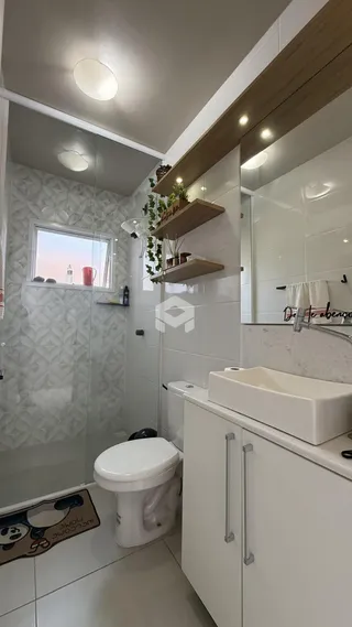 Banheiro moderno com revestimento branco e box de vidro.