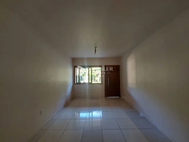 Corredor interno de uma residência com piso de cerâmica e paredes brancas.