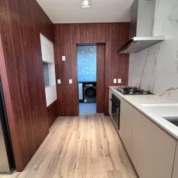 Hall de entrada com revestimento de madeira e piso de madeira clara.