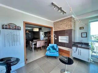 Interior de uma sala de estar com área de jantar e cozinha em um imóvel no Brasil.