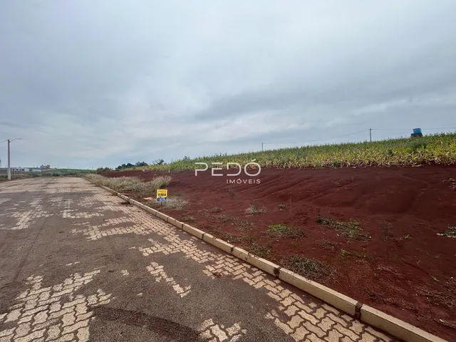 Vista externa de uma propriedade com terra vermelha e estrada no primeiro plano.