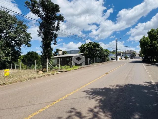 Vista da rua com vegetação e uma edificação ao fundo em Lajeado, Brasil.