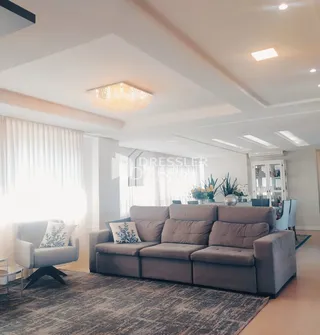 Sala de estar com um sofá grande e grandes janelas iluminadas.