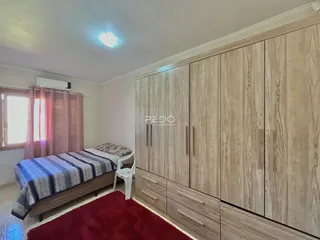 Quarto com cama e armários em madeira em um imóvel no Brasil.