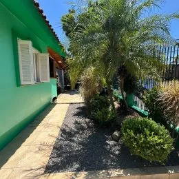 Foto da fachada de uma residência com vegetação tropical e calçada.