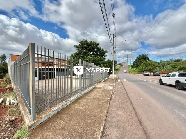 Foto da fachada de uma propriedade com cerca metálica ao lado de uma estrada.
