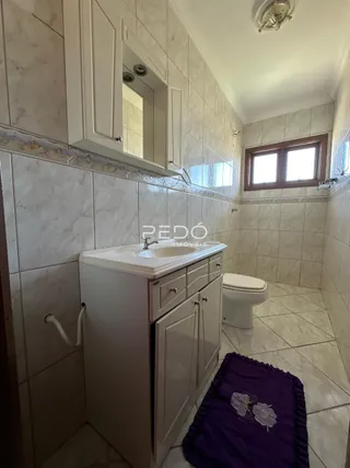 Foto de um banheiro com revestimento cerâmico e armário branco.