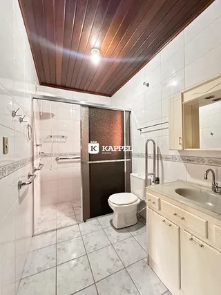 Um banheiro com revestimento branco e piso de cerâmica é visível na imagem.