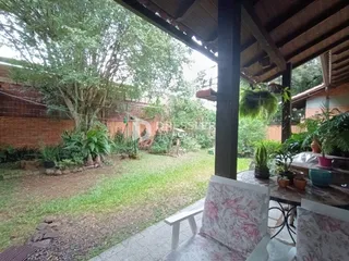 Vista do jardim lateral de uma propriedade em Lajeado, Brasil, com árvores e gramado.