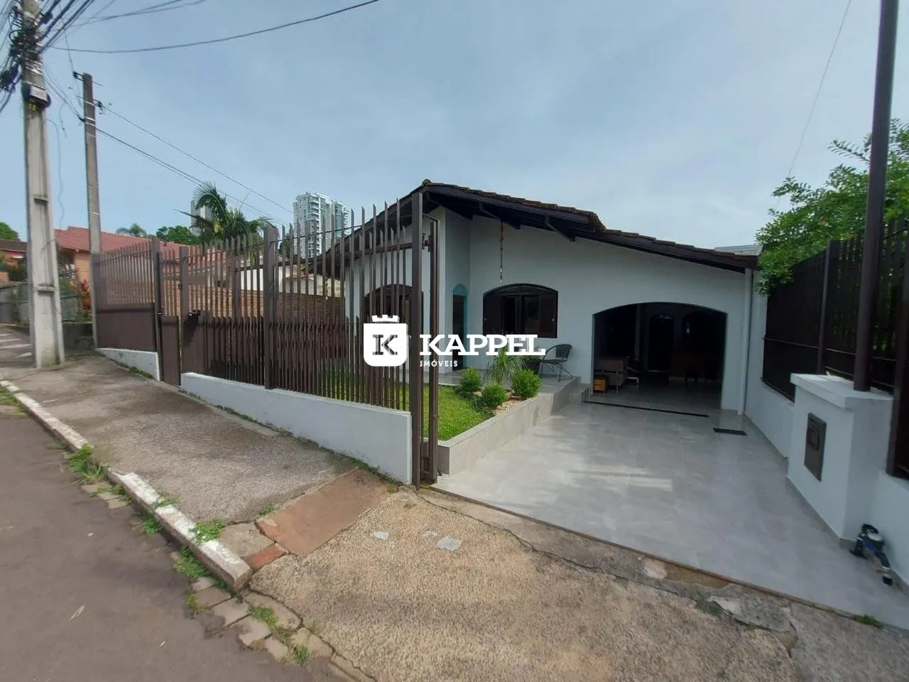 Fachada de uma residência com cerca e acesso pavimentado na rua.
