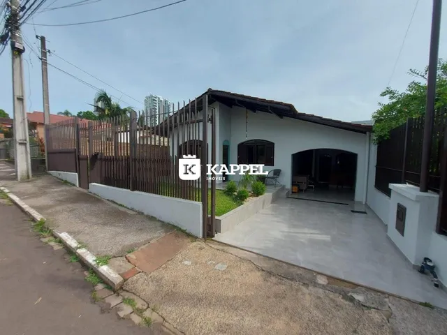 Fachada de uma residência com cerca e acesso pavimentado na rua.