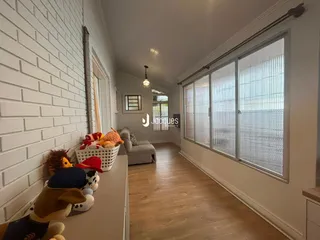 Hall de entrada com paredes de tijolo branco e piso de madeira.