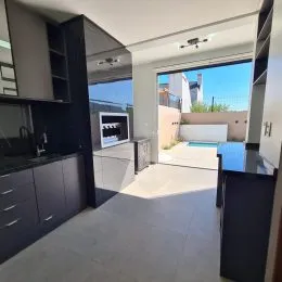 Vista interna de uma sala com piso claro e acesso a uma área externa.