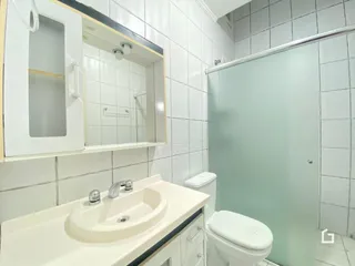 Foto de um banheiro com revestimento cerâmico branco.
