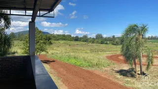 Uma vista externa mostrando um caminho de terra em direção a um campo aberto.