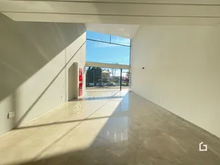 Espaço interno com paredes brancas e piso de concreto.