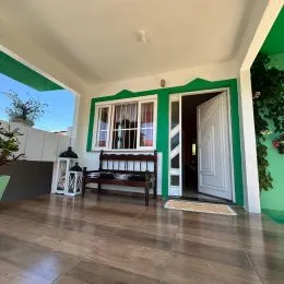 Sala de estar com piso de madeira e detalhes em verde na residência.