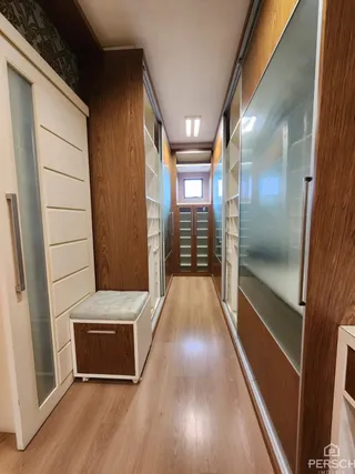 Um corredor interno com revestimento de madeira e armários em uma residência.