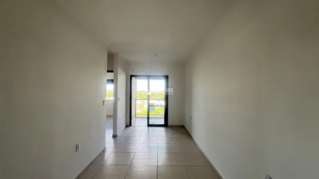 Corredor interno de uma residência com piso de cerâmica clara.