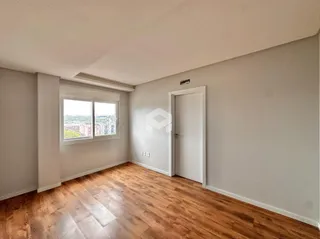 Vista interna de uma sala com piso de madeira e janela.