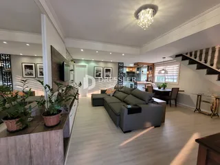 Sala de estar ampla com piso de madeira clara e sofá grande.