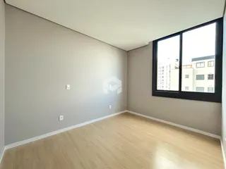 Sala de estar com piso de madeira clara e paredes cinzas.